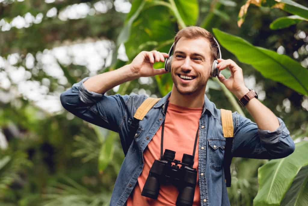 Guy listening to headphones in the rain forest