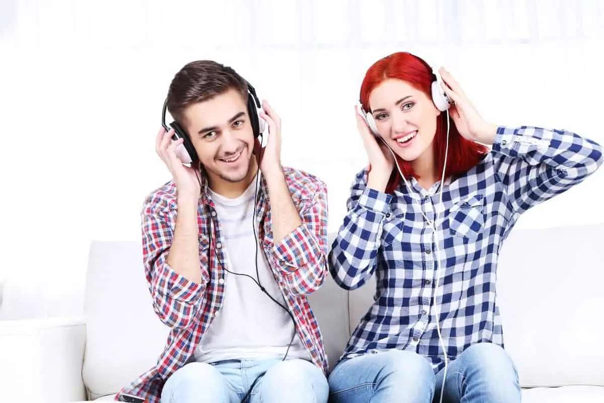 A couple sitting on a couch with headphones